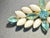 This DeLizza & Elster styled brooch combines smooth, opaque white milk glass navette cabochons with faceted aquamarine...
