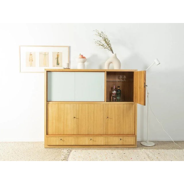 Wonderful highboard from the 1960s. Corpus in a bleached walnut veneer with four cupboard doors, three shelves, three...