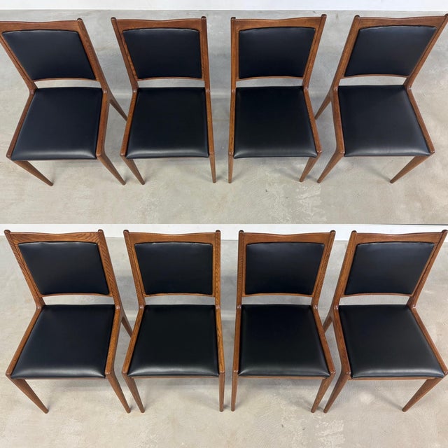 A beautiful set of 8 mid century modern oak frame dining chairs in a rich walnut stain and black vinyl seats....