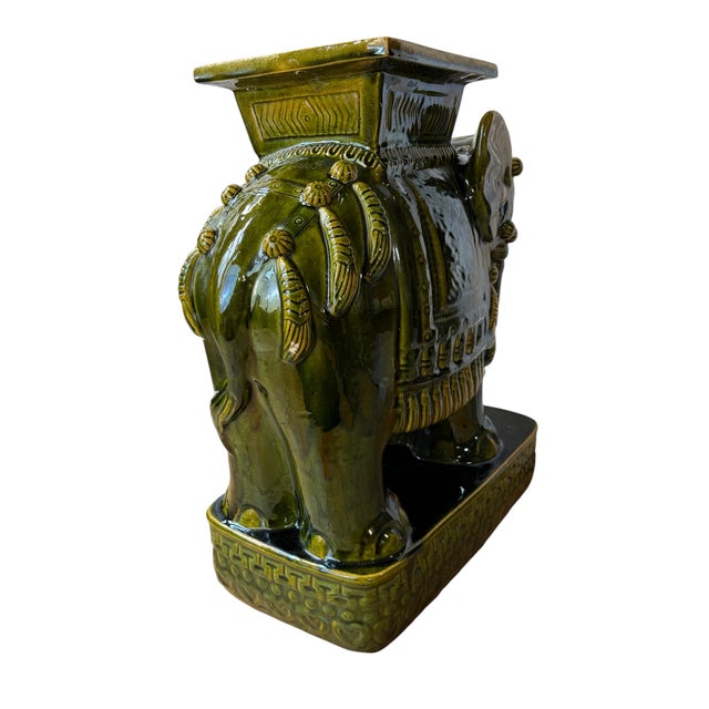 This is a mid-century glazed ceramic elephant garden stool or plant stand in a rich olive green glaze. The elephant is...