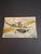 This rare early-20th-century Judaica greeting postcard depicts a stylishly dressed couple taking flight in a monoplane...