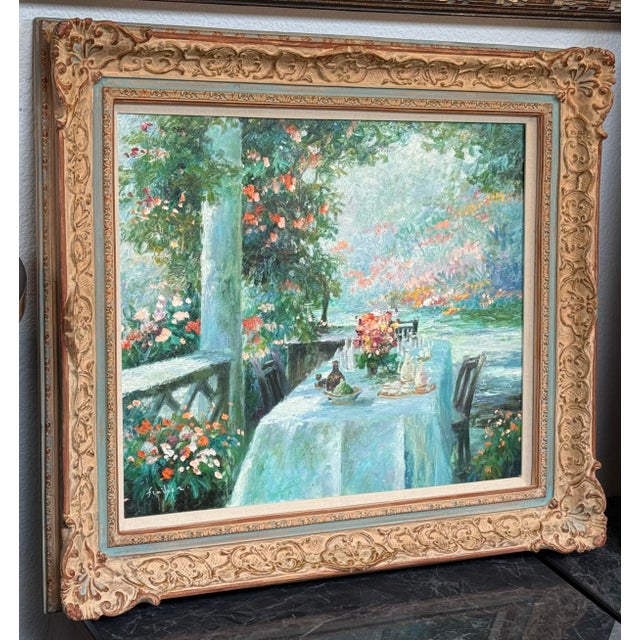 Design Plus Gallery presents a Still Life of a Dining Table on the Patio. The artwork has a signature that resembles...