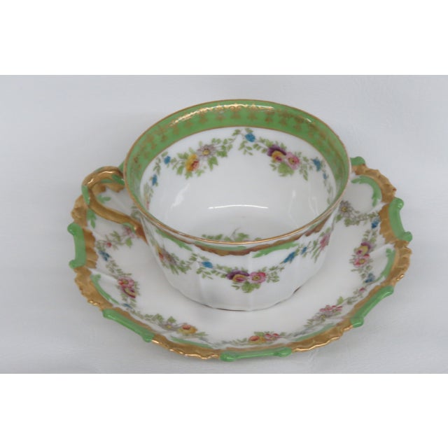 This lovely tea cup and saucer set is made of porcelain. Both pieces are white with a lining of green and gold details....