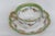 This lovely tea cup and saucer set is made of porcelain. Both pieces are white with a lining of green and gold details....