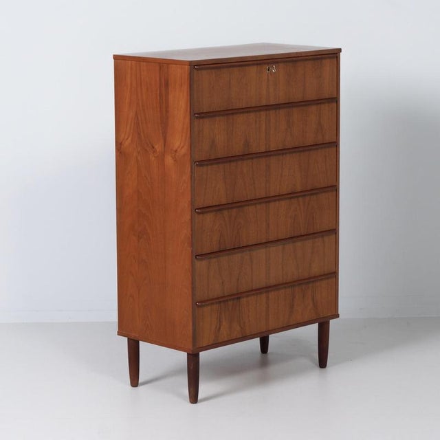 A Danish chest of drawers from the 1960s in warm teak, featuring a sleek Scandinavian mid-century design. The subtly...