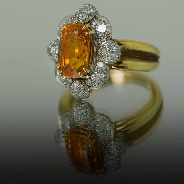 18K and platinum ring by Keith Davis set with one 3.98 carat orange sapphire and 24 round diamonds weighing 0.88 carats....