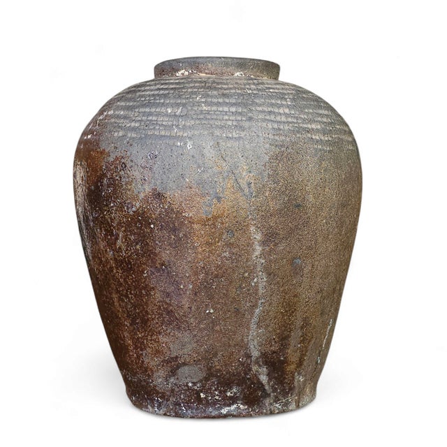 Vintage stoneware vessel with an oblong silhouette and deep earthen tones. The ribbed shoulder, smoke-fired glaze, and...