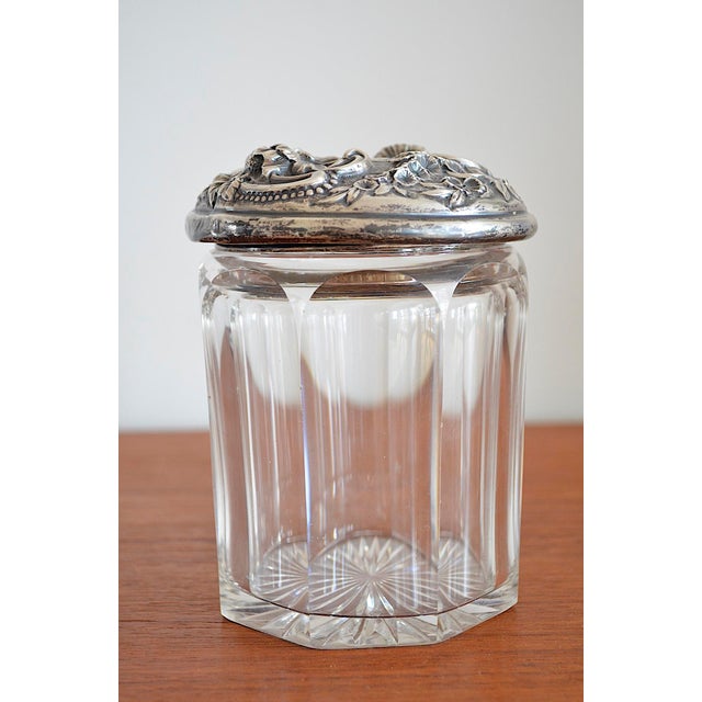 Sterling silver lidded box with a richly decorated floral design of hollyhocks, daisies, and forget-me-nots, interwoven...
