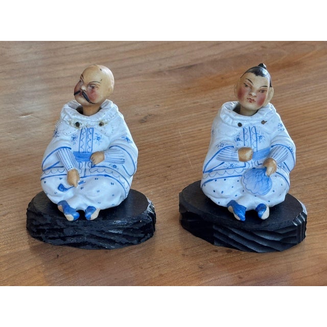 Pair of Chinese nodders seated cross legged in white robes painted with blue floral sprigs and banding, their heads...