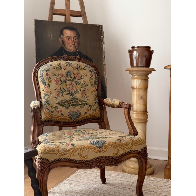 A beautiful antique French armchair in the Louis XV style, featuring a finely carved walnut frame, graceful cabriole legs,...
