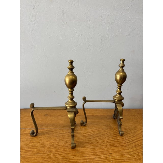 This handsome pair of vintage English brass andirons brings timeless formality and quiet grandeur to the hearth. The...