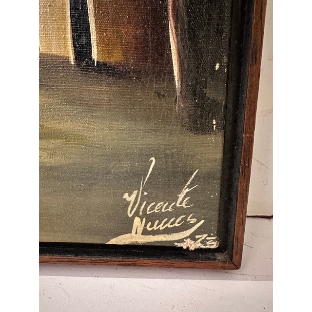 A Haitian village river scene in oil, signed and dated by the artist. The composition centers on a dugout canoe with two...
