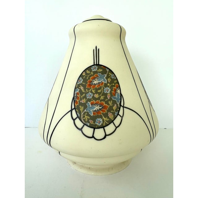 This elegant vintage lamp shade features a softly shaped cream-colored glass body decorated with hand-applied black...