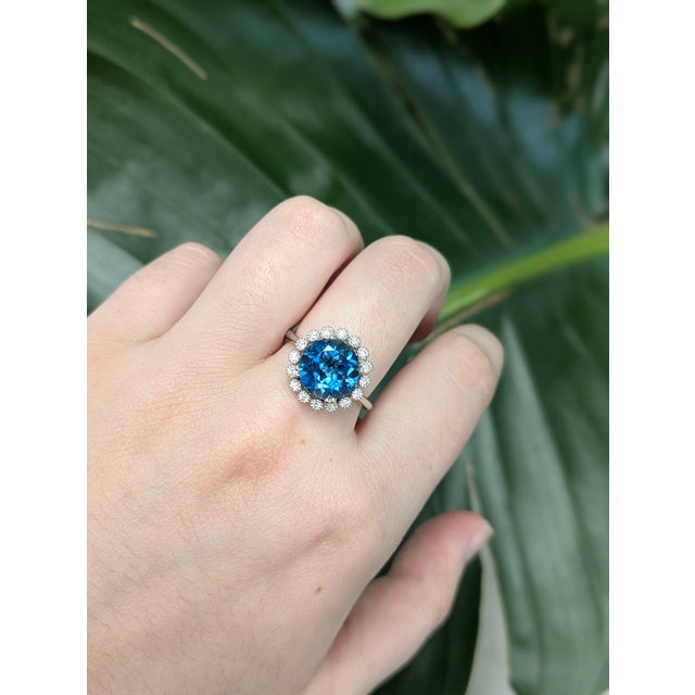This striking ring features a vibrant 4.25-carat London Blue Topaz, sourced from Brazil and treated with irradiation to...