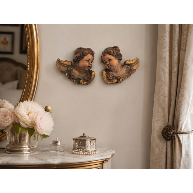Pair of antique hand carved Italian angels or putti with softly painted faces and gilded accents. Executed in the...