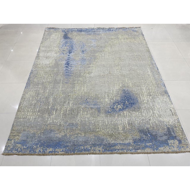 An 8' x 10' hand-knotted wool rug with a silver gray field washed with steel blue in a loose, painterly abstract. Newly...