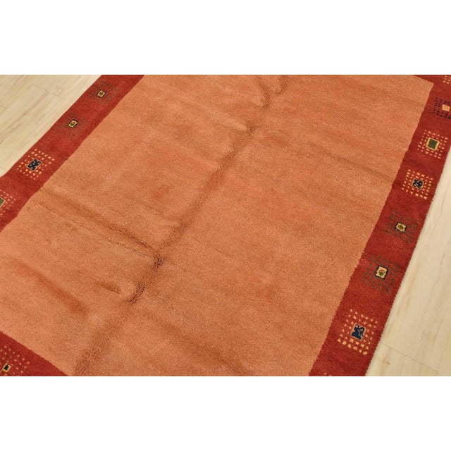 A contemporary Gabbeh rug, hand-knotted with fine wool on a cotton foundation. This rug features a solid orange background...