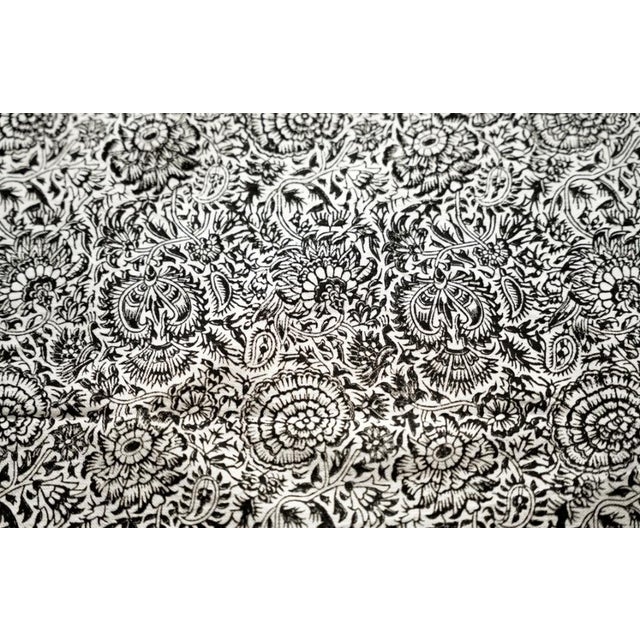 A rectangular cotton tablecloth with a monochrome floral pattern and a central sunburst motif. Hand block-printed using...