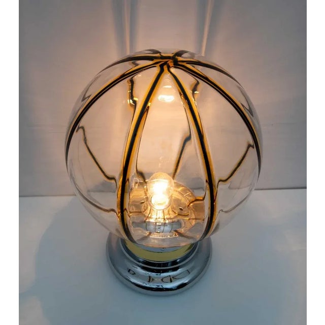 Murano glass lamp composed of a transparent glass globe with dark blue and yellow colorful bands. Cylindrical base with...