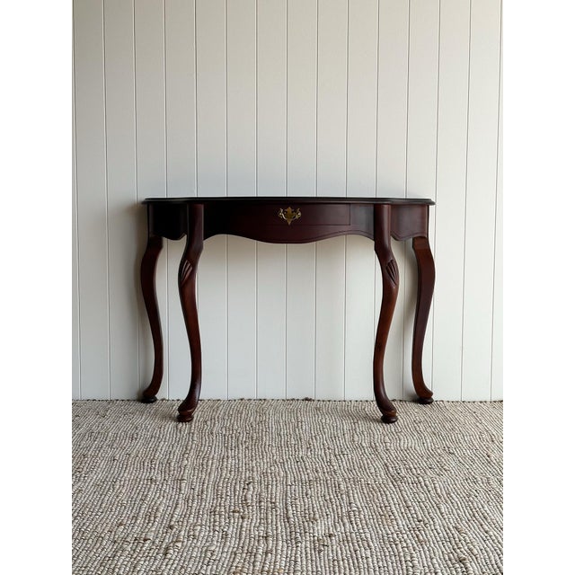 This vintage Queen Anne-style console table features a shaped serpentine front, long cabriole legs, and carved detailing...