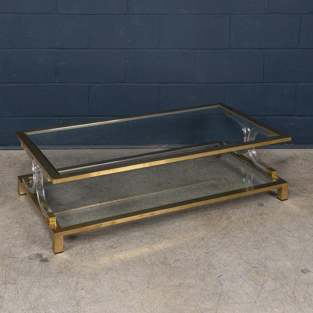 A striking Italian coffee table dating to the 1980s, executed in glass, brass and acrylic glass. The rectangular glass top...