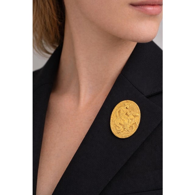Elegant Greek Revival brooch crafted in 18K yellow gold, designed as an oval relief plaque depicting a mythological figure...
