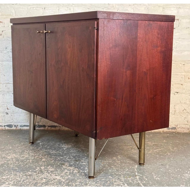 Efficiently-sized two-door storage cabinet. Composed of rich rosewood veneer, brass hairpin legs, & brass handles, the...