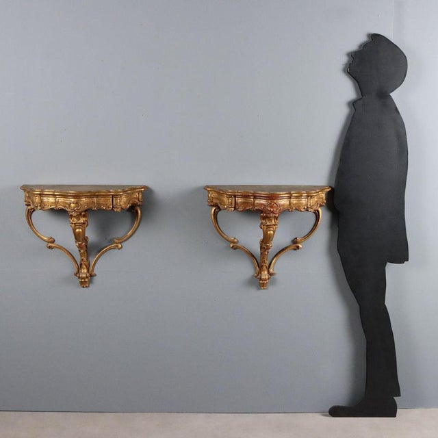 Pair of small drop-shaped consoles in carved and gilded wood, dating to the 20th century, featuring an elegant and refined...