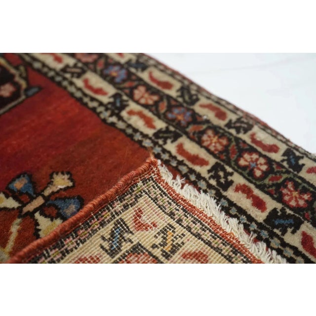 This well-woven west Persian village ruglet presents a crimson red field with navy weeping willow and vase motives, and a...
