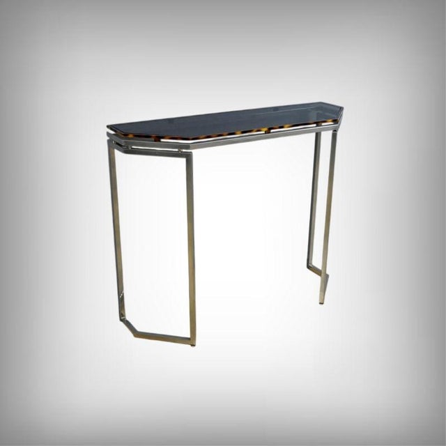 An elegant console table from the 1970s, characteristic of the period's modernist design. It features a subtly tinted,...