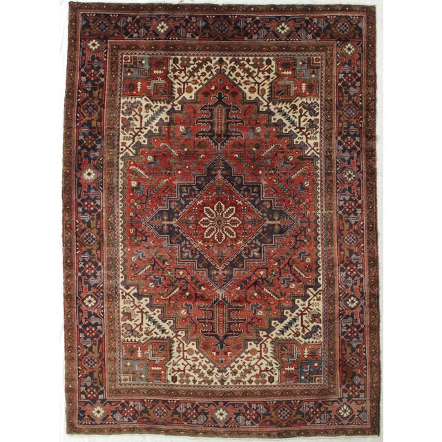 Vintage hand-knotted Persian Heriz wool rug with a red field centered by a large geometric medallion in navy, ivory, and...