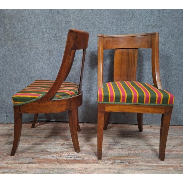 A pair of Empire period chairs in solid walnut, with a simple and elegant design characteristic of the early 19th century....