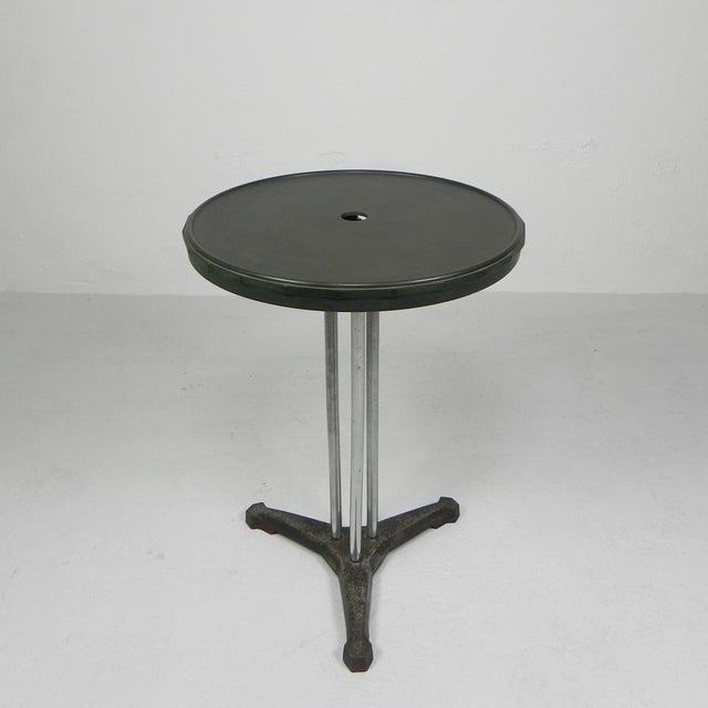 Height: 72 cm. Ø: 51 cm. The Bakelite top has a hole for a parasol. Origin: France, 1930s. Material: cast iron / aluminum...