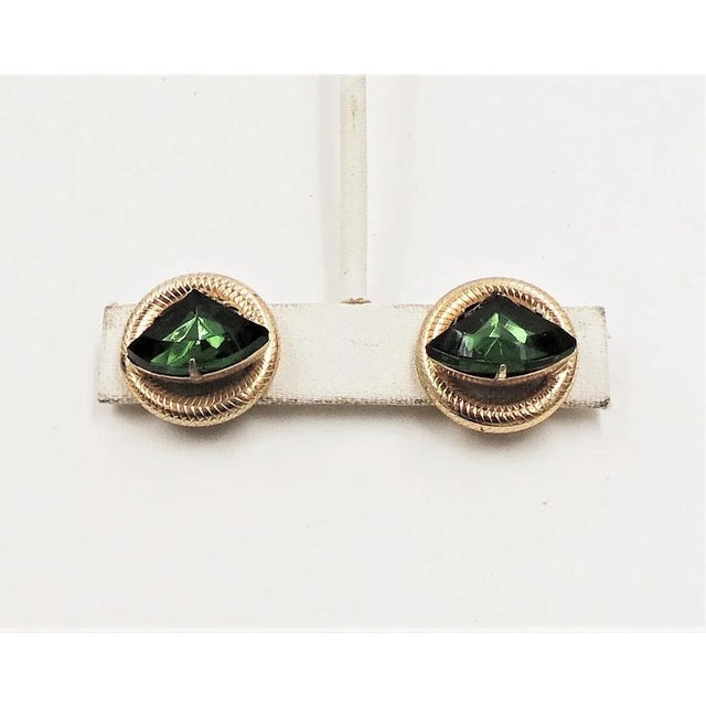 This is part of Chairish’s Costume Jewelry assortment. 1950s round goldtone triangular shaped faux-emerald butterfly clip...