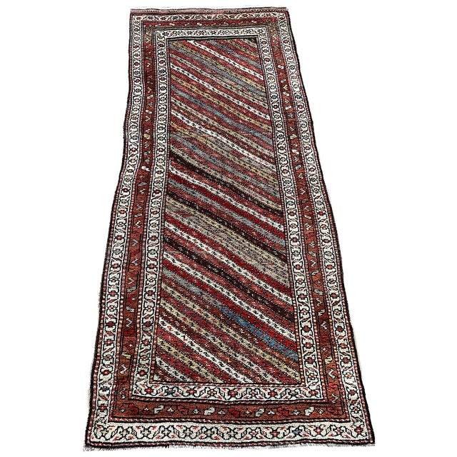 A beautiful antique Kurdish runner, hand woven circa 1900. The design features a series of multicoloured diagonal bands...