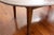 An antique oval dining table in dark stained mahogany with visible grain, subtly shaped edge and tapered square legs. No...