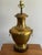 A midcentury Hollywood Regency polished brass urn table lamp with foo-dog ring handles on a dark wood plinth, classic...