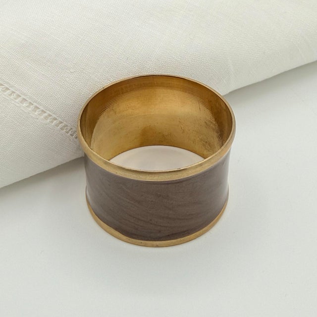 A quietly elegant set of eight vintage napkin rings combining warm brass with a smoky taupe-brown marbled finish. The...