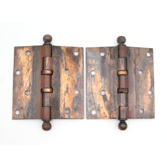 This pair of ball bearing hinges is made of dark brass and copper plated brass with ball tips, five knuckles, and a...