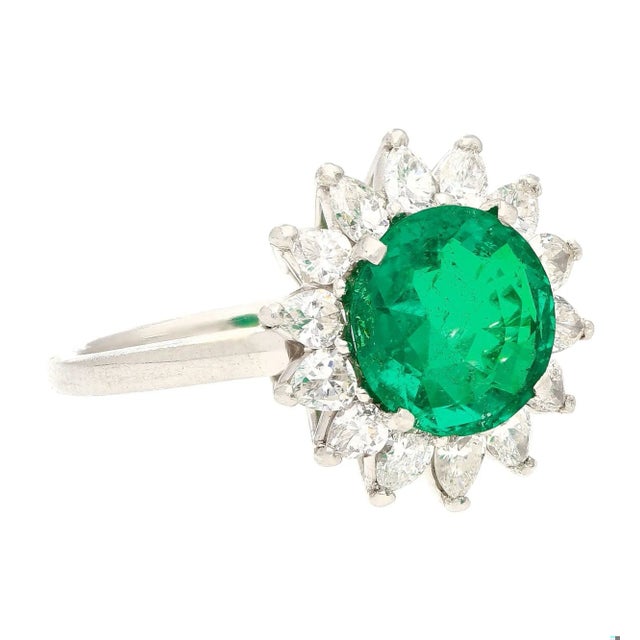 GRS-certified platinum engagement ring, centering a 3.02-carat natural emerald and 1 carat total natural diamond halo. The...