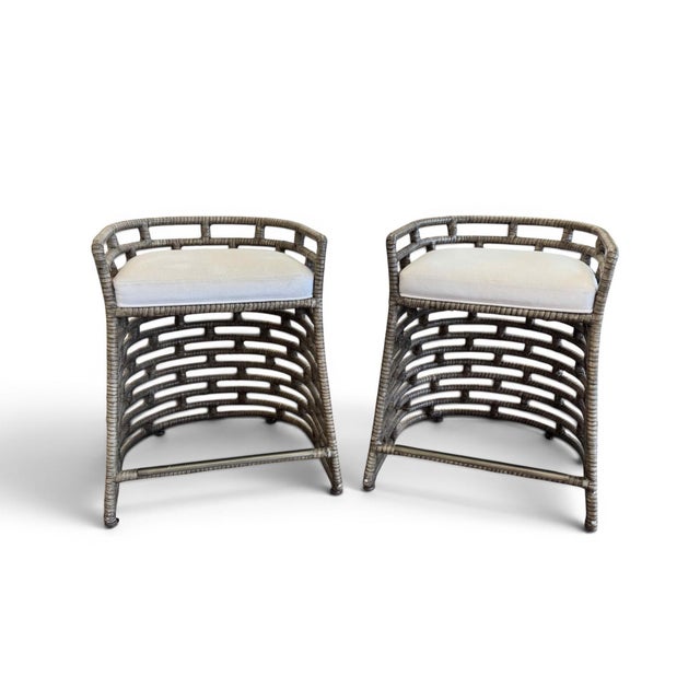 A pair of Palecek Thatcher counter stools. Features a metal frame hand-wrapped with rattan peel in a grey finish. The...