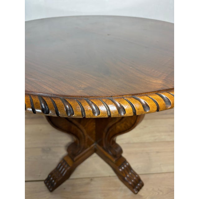 Elegant round side table crafted in richly figured walnut, featuring a sculptural pedestal base with flowing scroll...