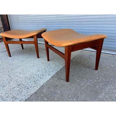 A pair of teak foot stools in new tan leather. As a bonus, the footstools come apart, which makes it very easy to ship...