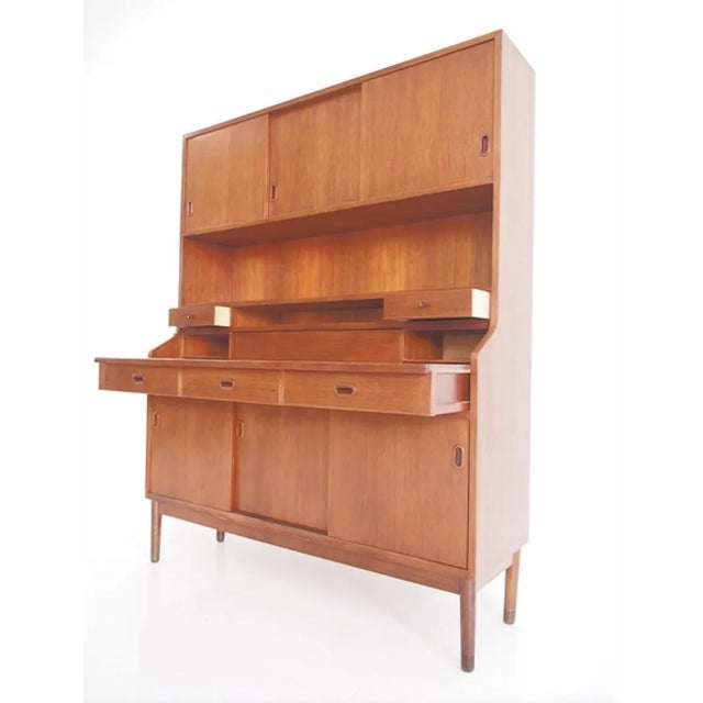 Veneered teak cabinet, buffet or secretary. Front top: three doors behind which are shelves and pullout trays. Bottom:...