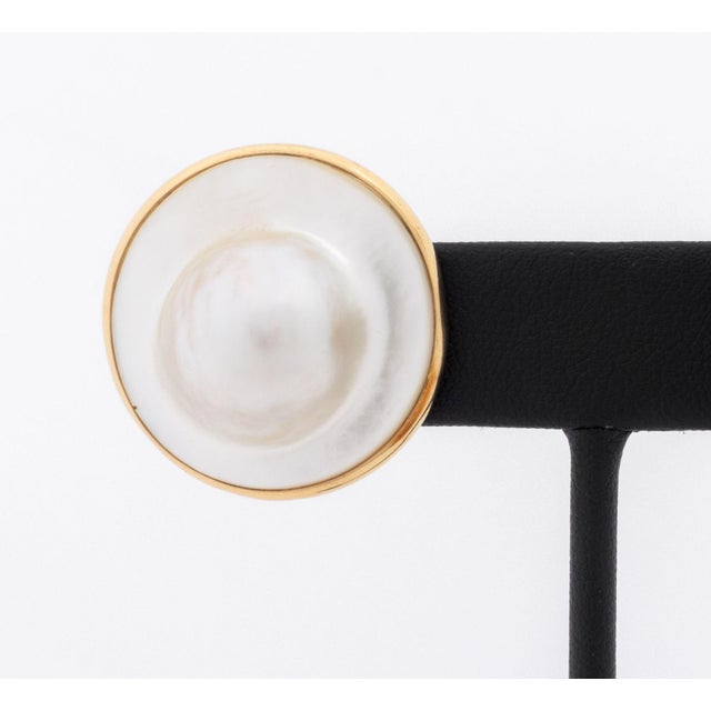 Pair of Modern Mabe Blister Pearl and 14K Yellow Gold Earrings, designed as round shaped earrings, featuring two bezel set...