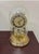 A 9-inch-tall gold quartz anniversary dome clock by Linden with roman numerals and a rotating pendulum mechanism. It's...