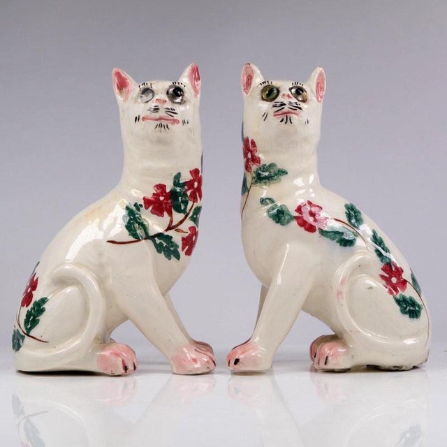 Boldly modelled in an alert seated posture, this pair of ceramic mantel cats displays the characterful folk charm...