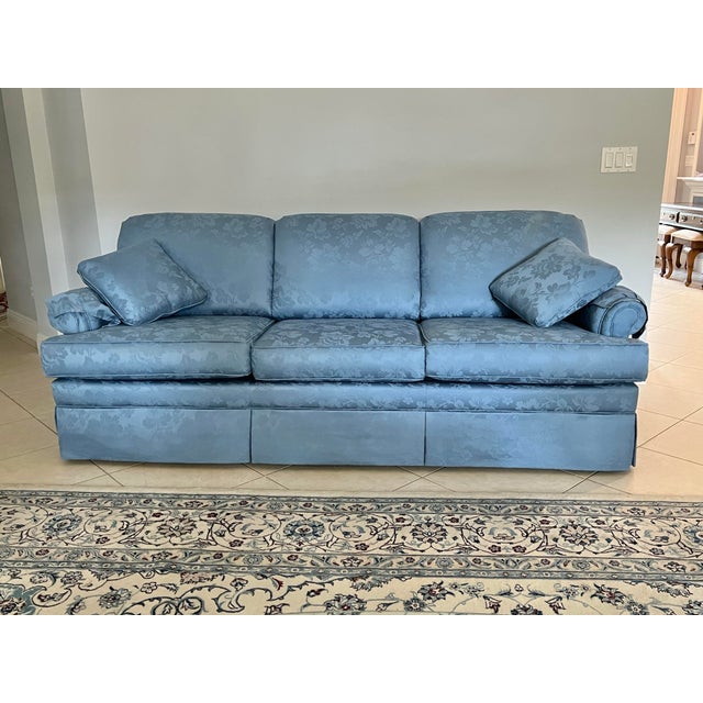 Vintage three cushion skirted sofa featuring rolled arms and blue floral damask upholstery. Comes with Two arm covers and...