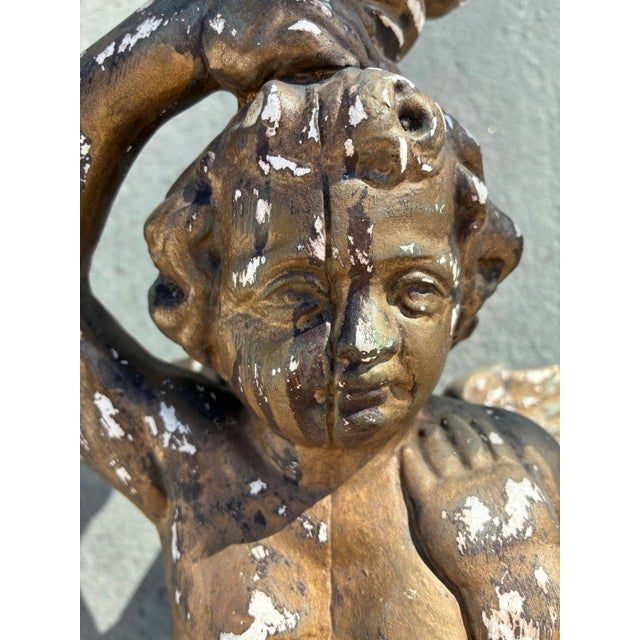 A dramatic and sculptural Rococo Revival wall bracket featuring a winged cherub in raised-arm pose supporting a round...