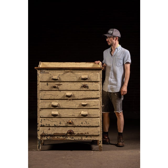Painted wooden cabinet featuring seven full-width drawers housed within a beadboard case with shaped gallery back and a...